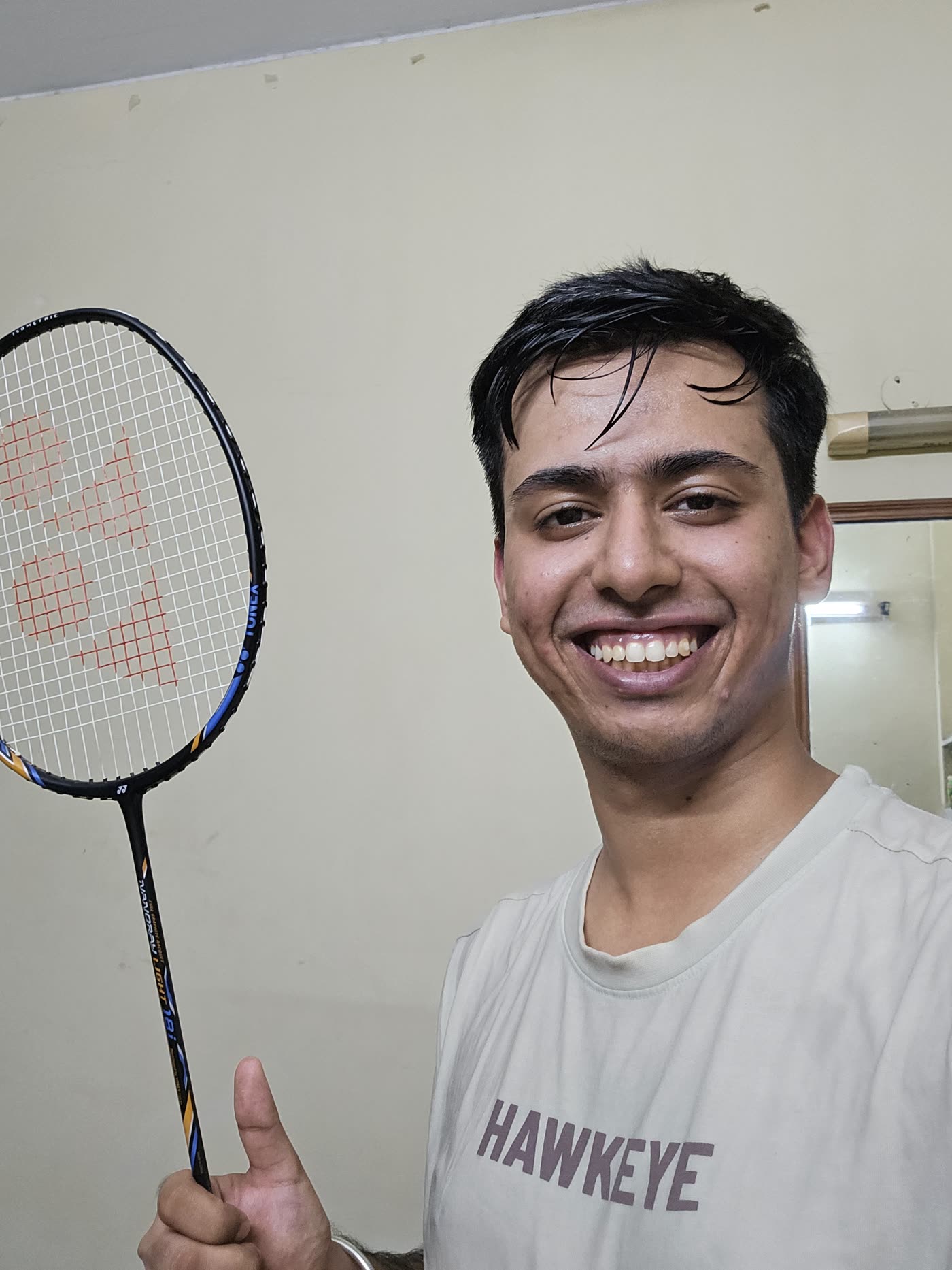 Aryan grinning, holding up a badminton racket and a thumbs up