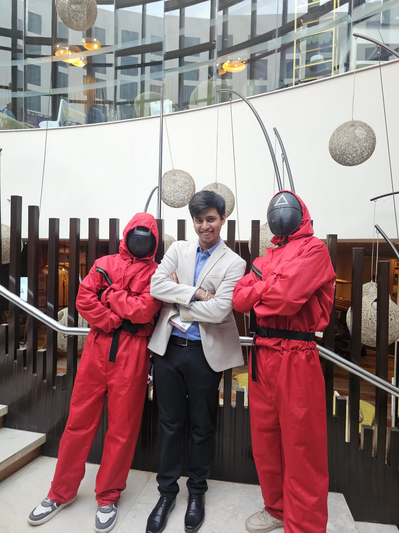 Aryan in a suit, arms crossed, between two people dressed as Squid Game guards at AISS 2025 in New Delhi